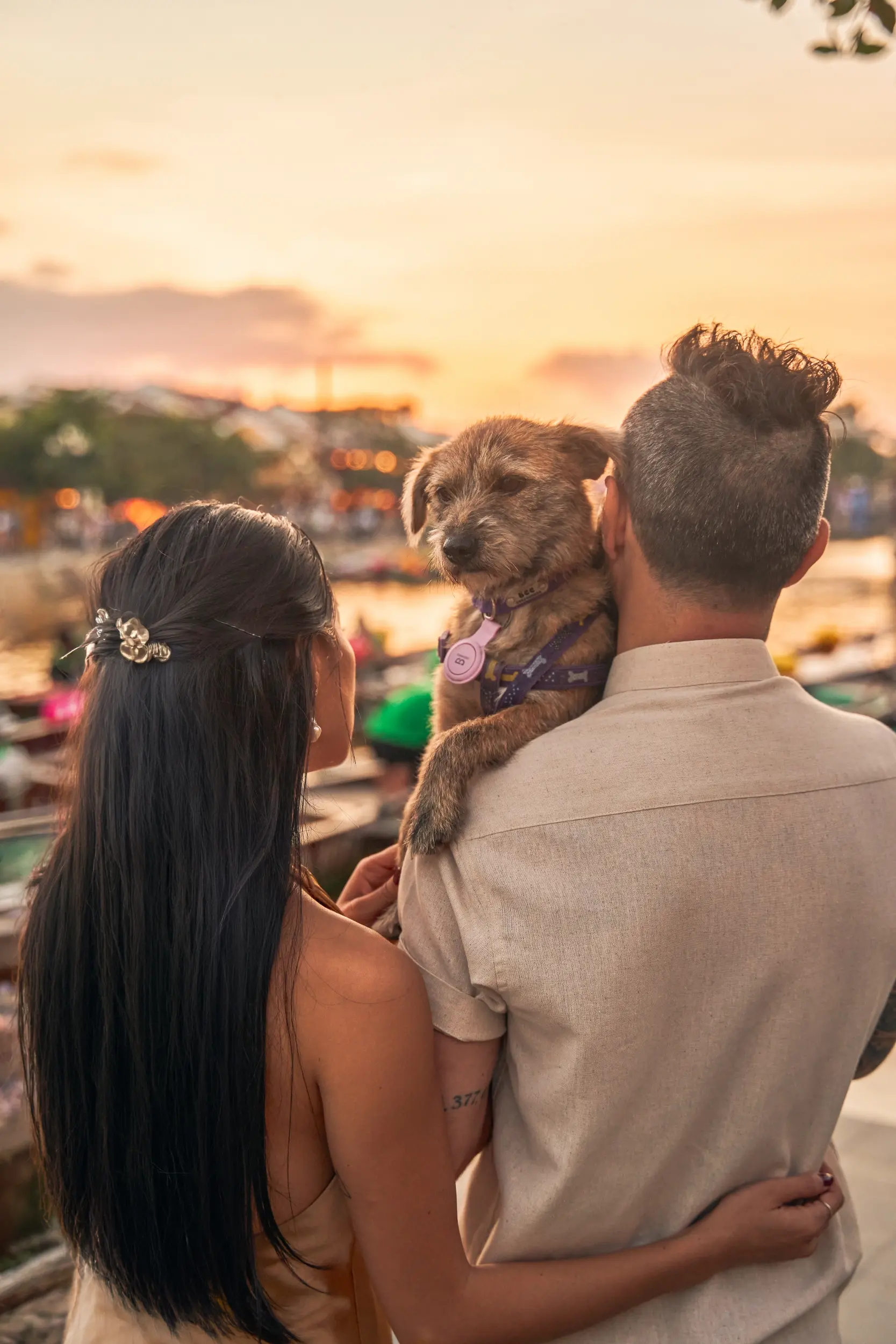 Mai and Gian with their dog, looking out over Hoi An at sunset